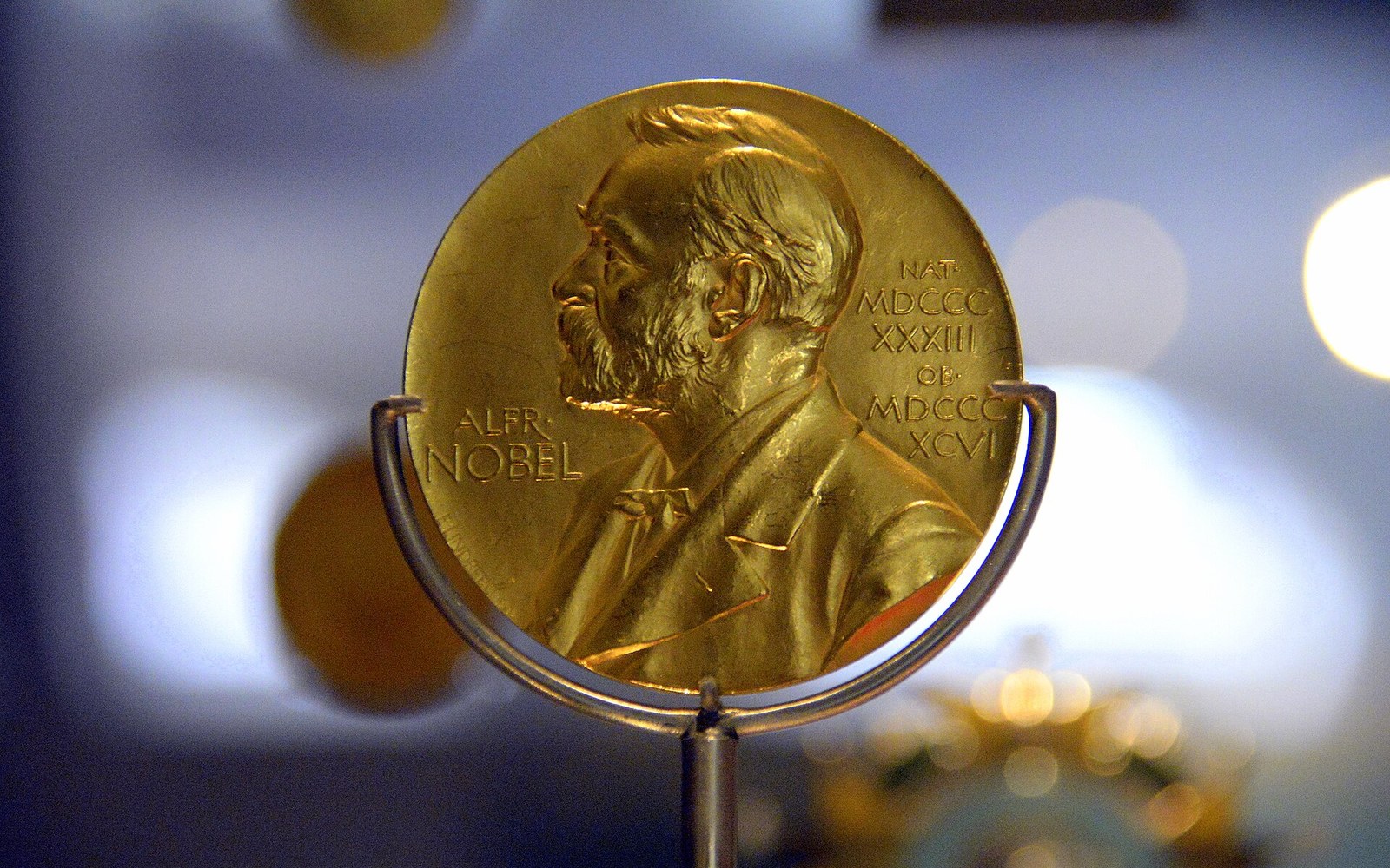 Gold Nobel Prize medal engraved with the profile of Alfred Nobel, displayed on a stand