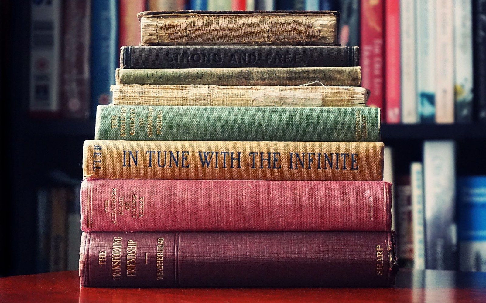 Stacked hardcover books with worn spines, including titles like "In Tune with the Infinite"