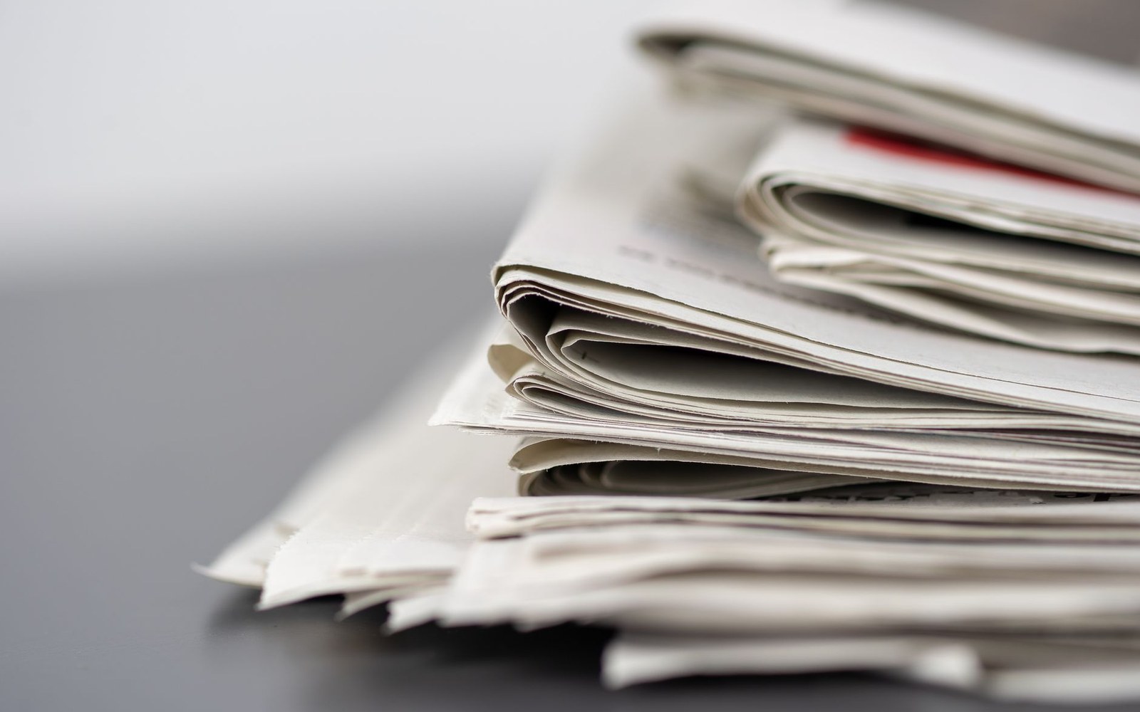 Close-up of a folded stack of newspapers resting on a dark table