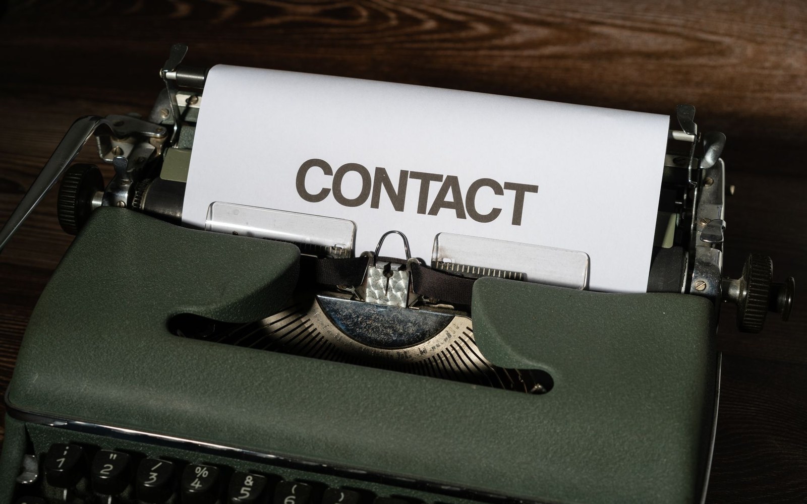 A vintage typewriter with paper reading "contact" rolled into the carriage