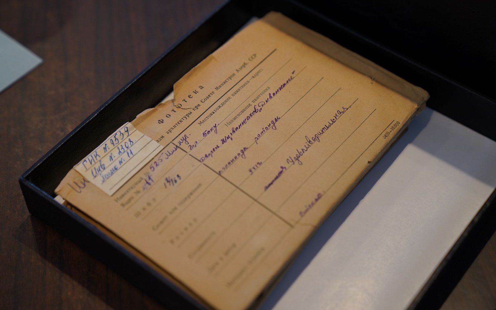 An archive box open to reveal folded samizdat typescripts, carbon paper edges visible, on a reading-room table
